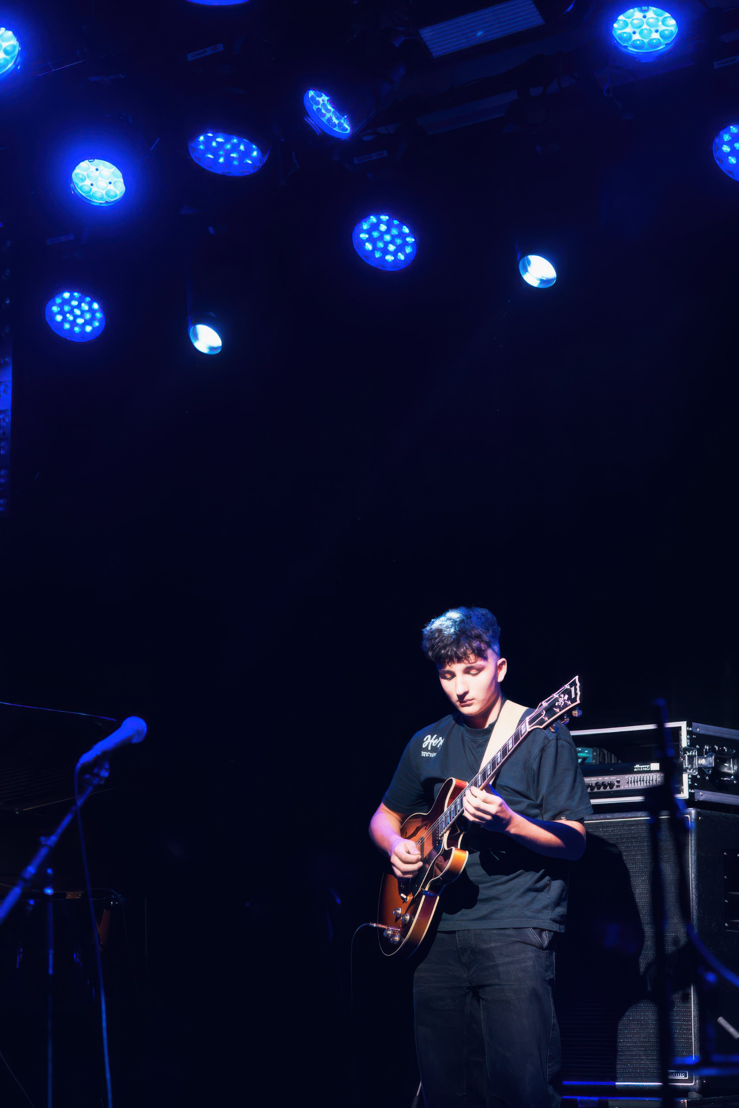An electric guitarist in blue stage light.