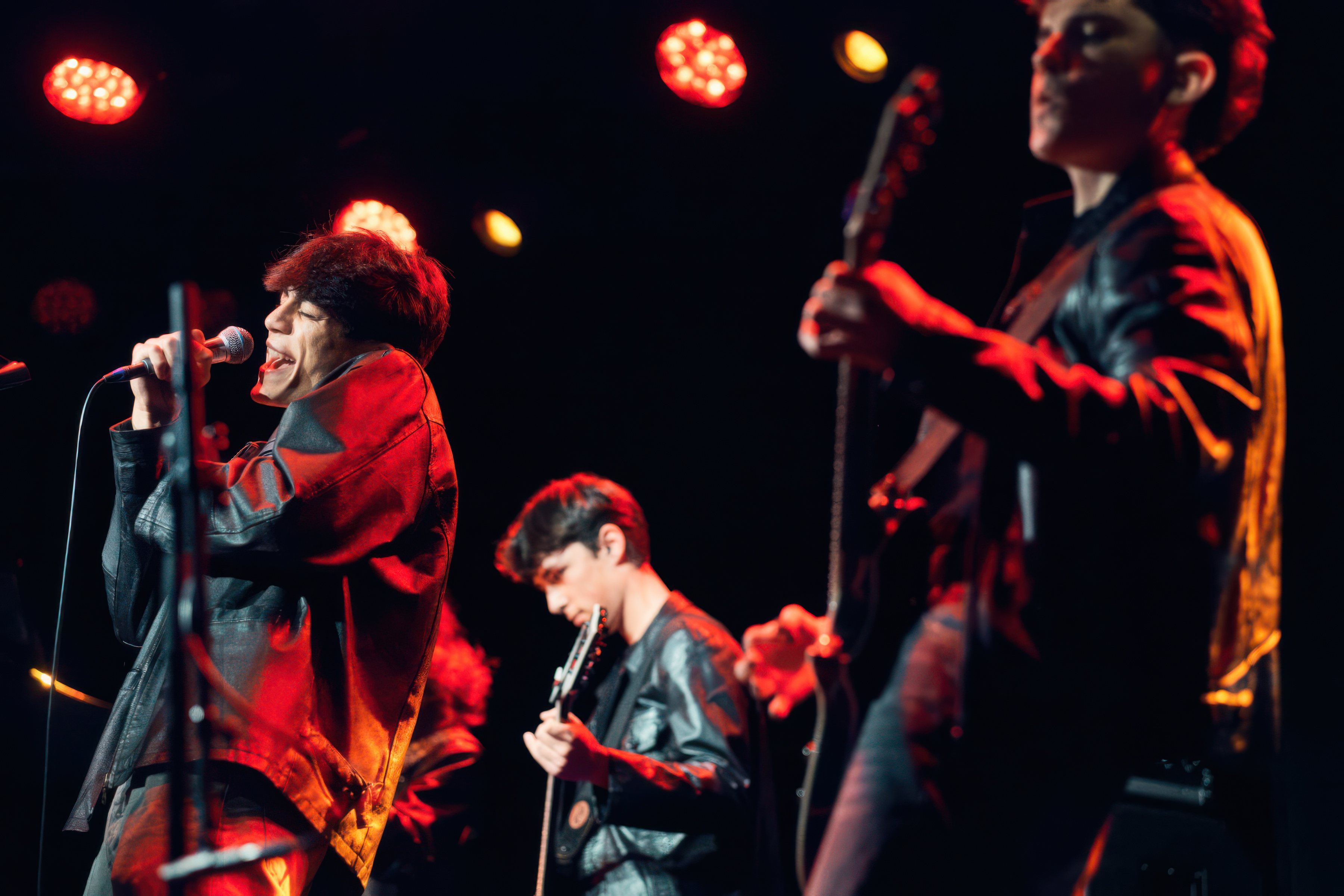A singer and band in red stage light.